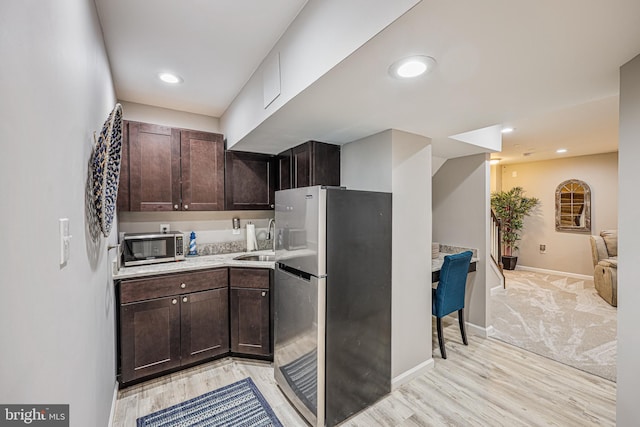 kitchen featuring dark brown cabinetry, light countertops, appliances with stainless steel finishes, and a sink