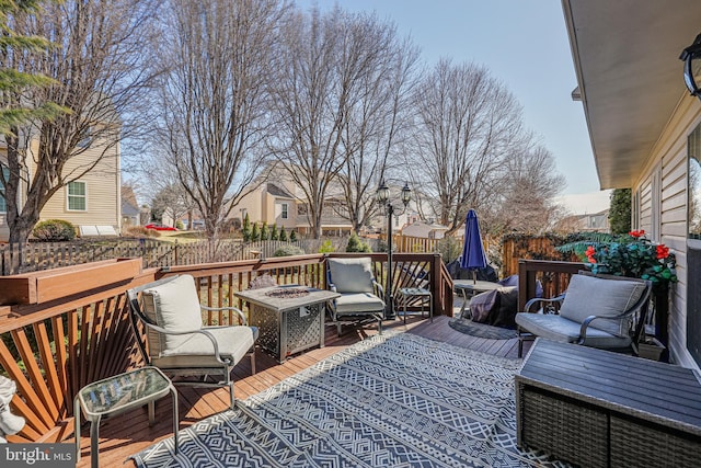 deck featuring an outdoor living space with a fire pit and fence