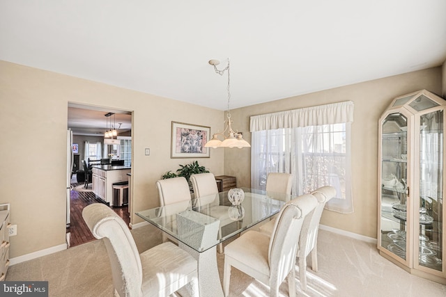 dining area featuring baseboards and light carpet