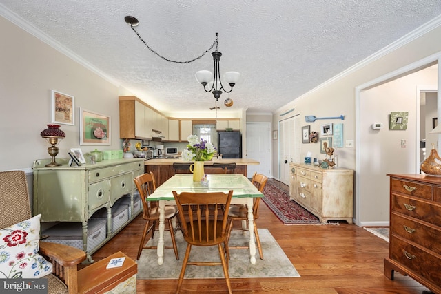 dining room featuring a textured ceiling, an inviting chandelier, wood finished floors, and crown molding