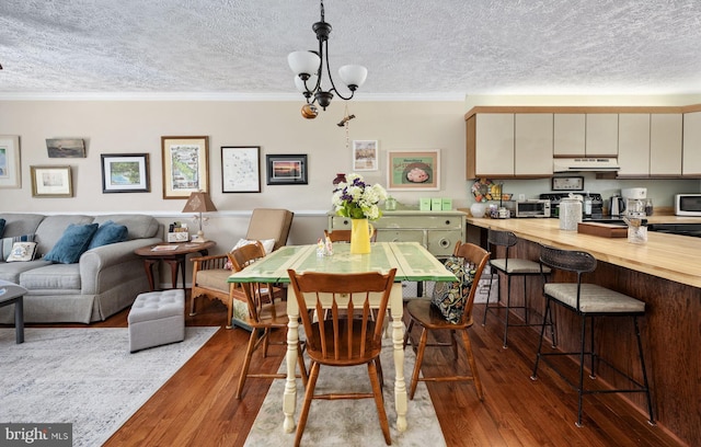 dining area with a chandelier, ornamental molding, a textured ceiling, and hardwood / wood-style floors