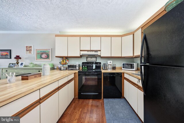 kitchen with black appliances, light countertops, extractor fan, and wood finished floors