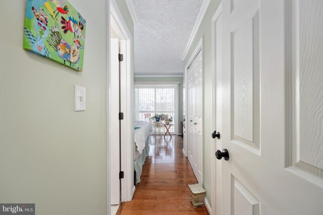 corridor featuring ornamental molding, light wood-style floors, and a textured ceiling