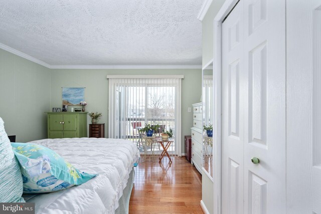 bedroom featuring light wood finished floors, a textured ceiling, crown molding, and access to outside