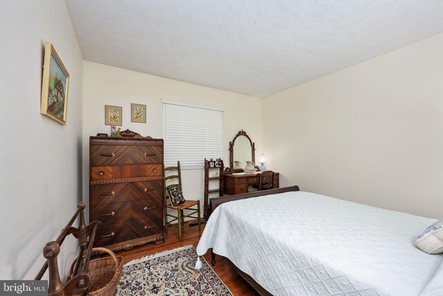 bedroom with a textured ceiling and dark wood finished floors