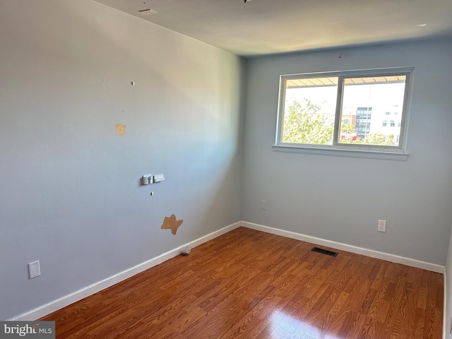 unfurnished room with wood finished floors, visible vents, and baseboards