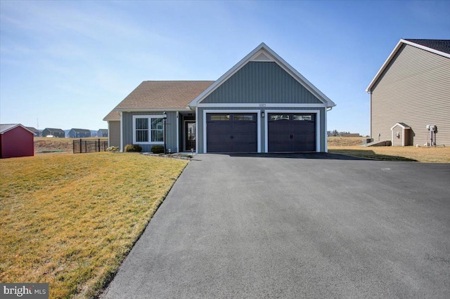 view of front of home featuring a front yard, fence, driveway, an attached garage, and board and batten siding