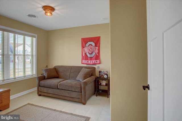 living room featuring light tile patterned flooring, visible vents, and baseboards