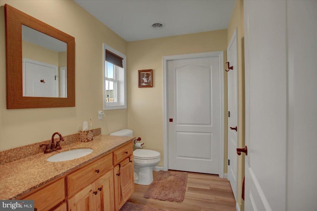 bathroom with visible vents, toilet, wood finished floors, baseboards, and vanity