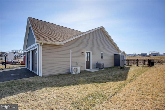 back of property with aphalt driveway, ac unit, a yard, and fence