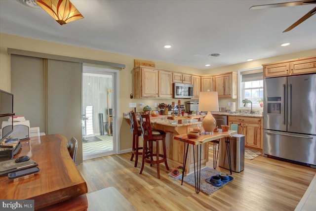 kitchen with a sink, light wood-style flooring, light brown cabinetry, and stainless steel appliances