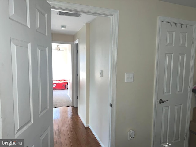 hallway with dark wood-style floors, visible vents, and baseboards