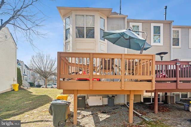 rear view of property with central AC unit, a wooden deck, and a lawn