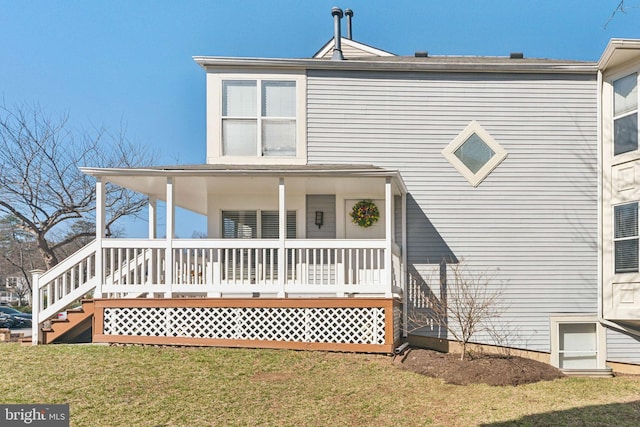 rear view of property with covered porch and a lawn