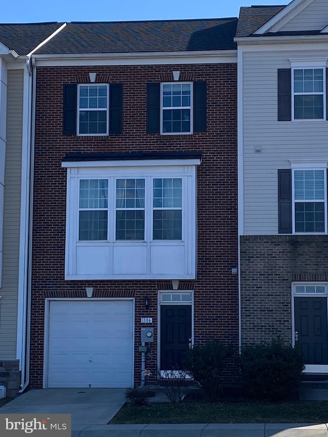 townhome / multi-family property featuring brick siding and driveway