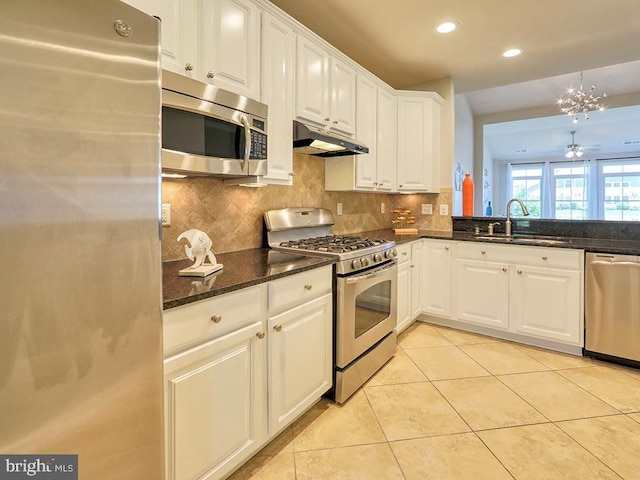 kitchen with under cabinet range hood, light tile patterned floors, appliances with stainless steel finishes, white cabinetry, and a sink