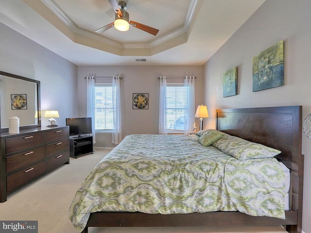 bedroom with visible vents, a raised ceiling, light colored carpet, and crown molding