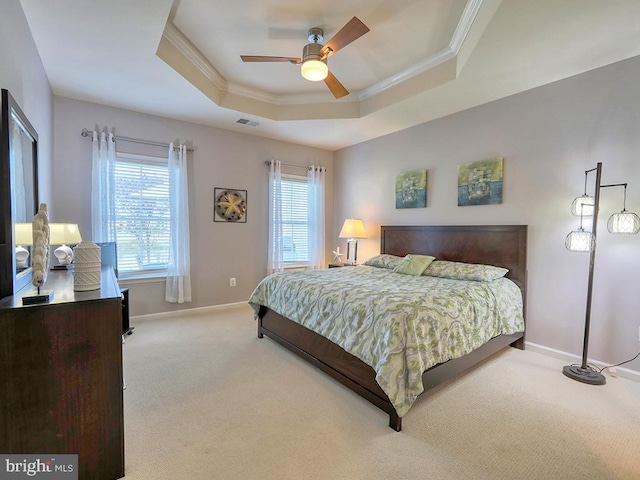 bedroom with light carpet, visible vents, a tray ceiling, and ornamental molding