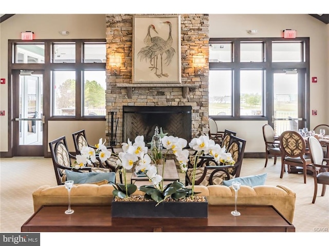 living area with baseboards, light carpet, and a stone fireplace