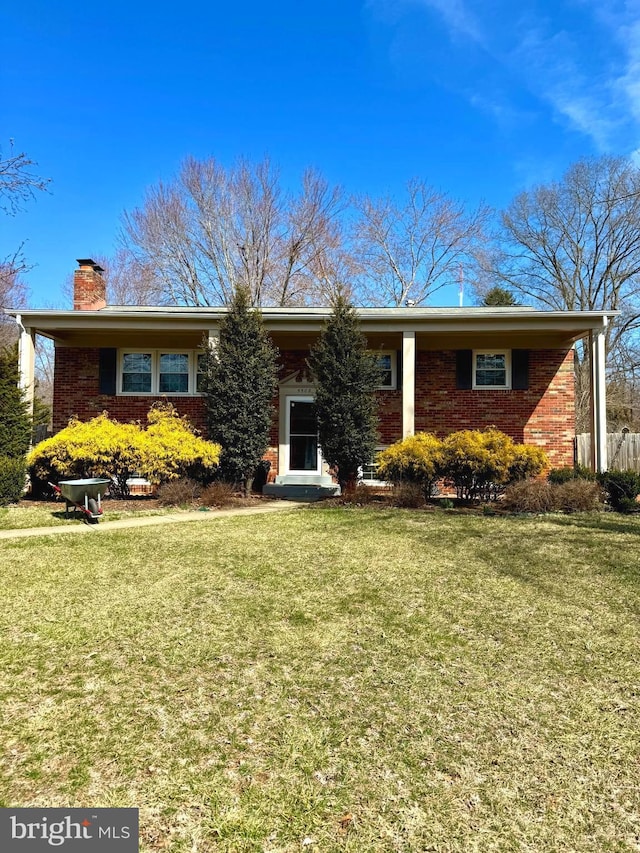 ranch-style home featuring brick siding, a chimney, and a front yard