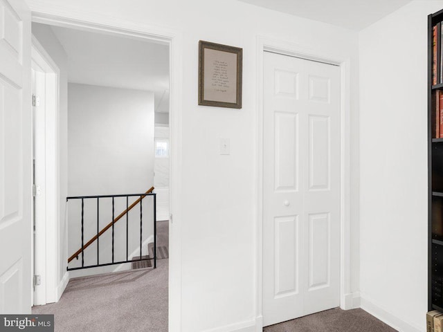 hall featuring carpet flooring, an upstairs landing, and baseboards