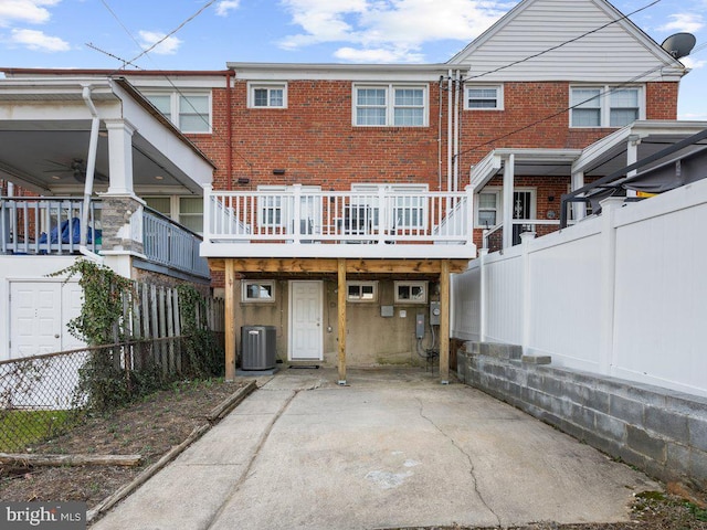 back of property with cooling unit, brick siding, a deck, and fence