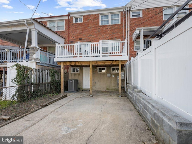 rear view of house featuring cooling unit, brick siding, and fence