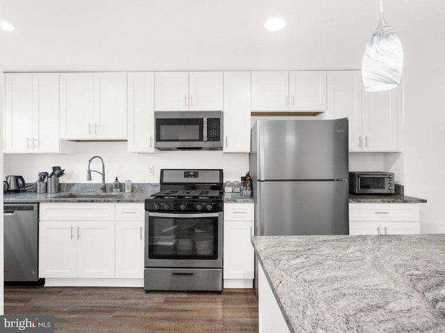 kitchen featuring a sink, light stone counters, appliances with stainless steel finishes, and white cabinetry