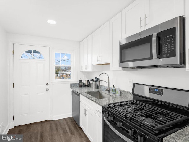 kitchen featuring light stone counters, appliances with stainless steel finishes, white cabinetry, and a sink