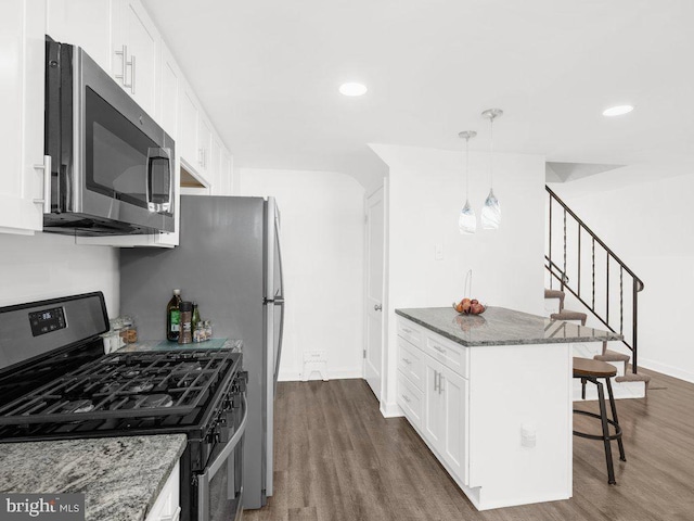 kitchen featuring white cabinetry, appliances with stainless steel finishes, a breakfast bar, and dark stone counters