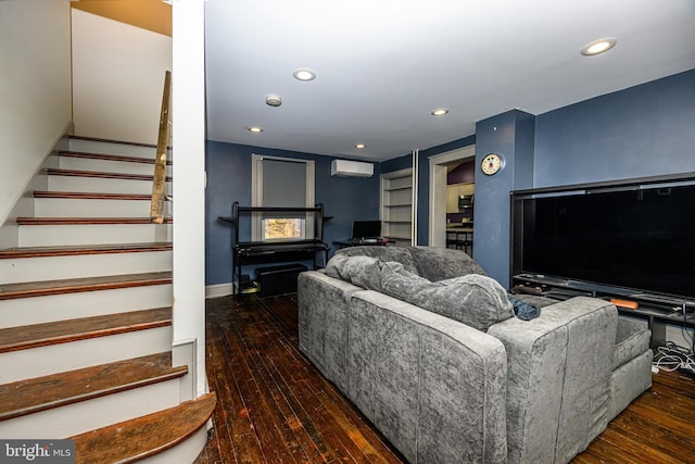 living area featuring a wall mounted air conditioner, built in shelves, hardwood / wood-style floors, recessed lighting, and stairs