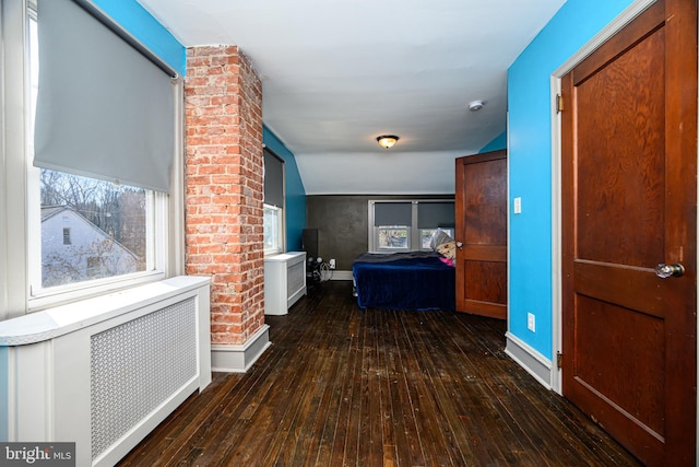 hall featuring baseboards, wood-type flooring, radiator heating unit, and vaulted ceiling