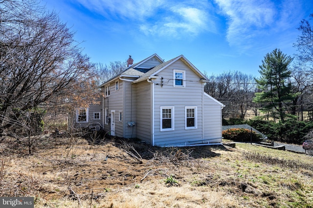 view of side of home featuring a chimney and roof with shingles