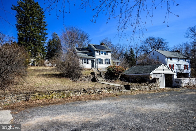 view of front of house with solar panels, an outdoor structure, and a chimney