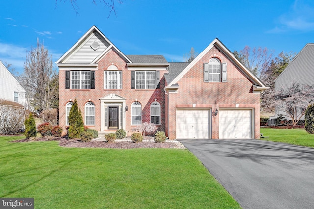 colonial house with a front yard, brick siding, an attached garage, and driveway