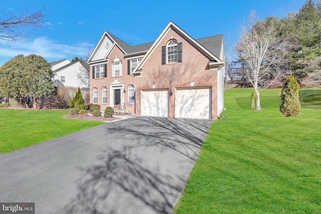 view of front of property with brick siding, driveway, an attached garage, and a front yard