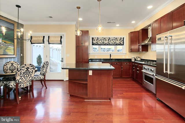 kitchen featuring dark countertops, appliances with stainless steel finishes, wall chimney exhaust hood, and a sink