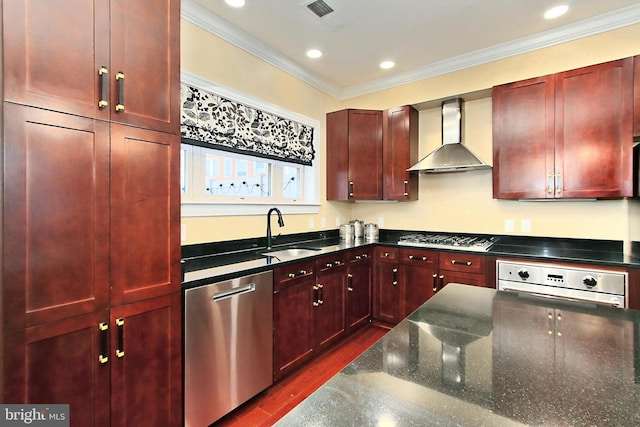 kitchen with visible vents, a sink, wall chimney range hood, stainless steel appliances, and reddish brown cabinets