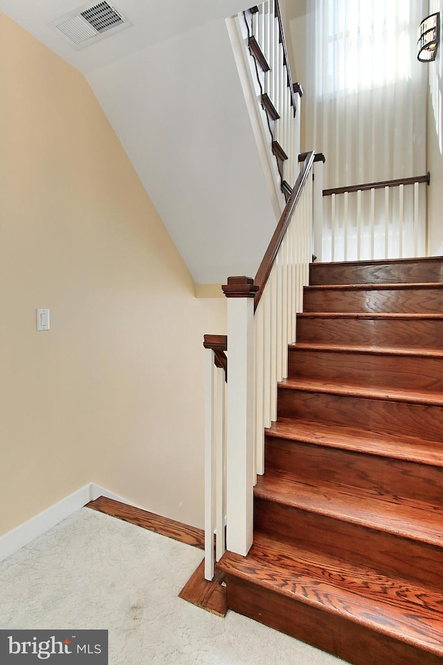 staircase with visible vents, baseboards, carpet, and vaulted ceiling