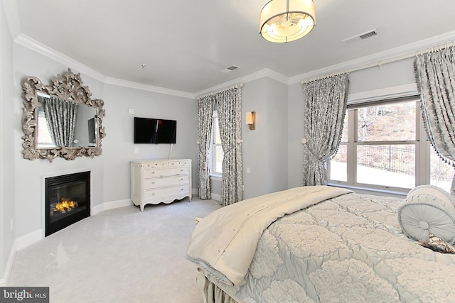 carpeted bedroom featuring visible vents, baseboards, a glass covered fireplace, and ornamental molding