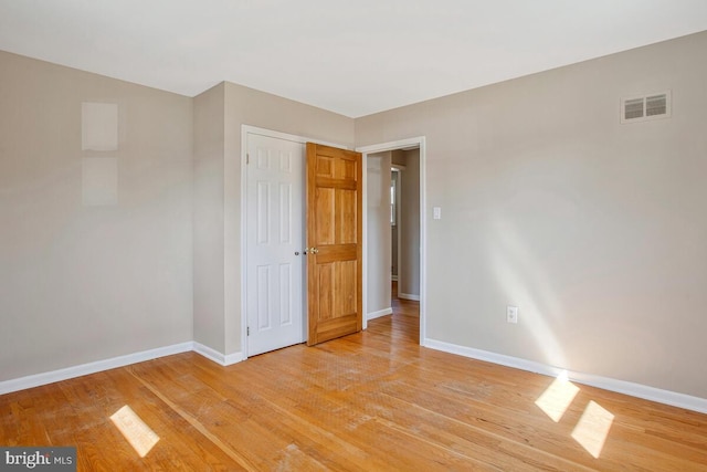 unfurnished bedroom with light wood-style flooring, baseboards, visible vents, and a closet