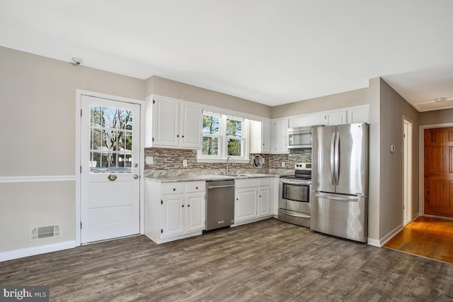 kitchen featuring visible vents, dark wood-type flooring, decorative backsplash, appliances with stainless steel finishes, and white cabinetry