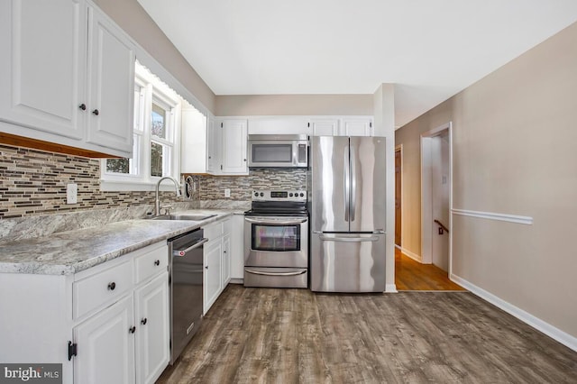 kitchen featuring dark wood-type flooring, decorative backsplash, stainless steel appliances, white cabinetry, and a sink