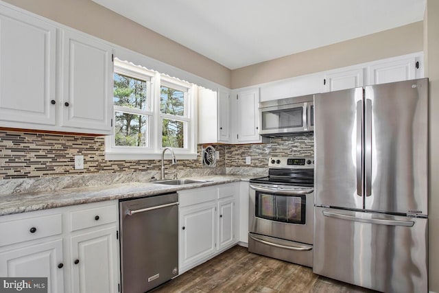 kitchen featuring a sink, backsplash, white cabinetry, appliances with stainless steel finishes, and light countertops