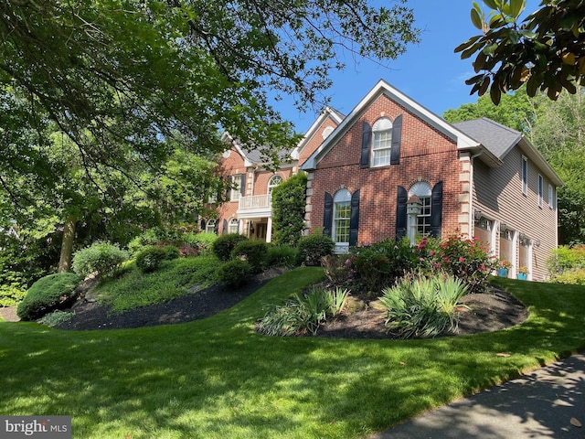 view of front of property with a front lawn, an attached garage, and brick siding