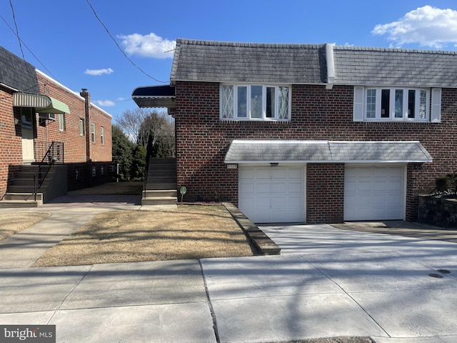 view of front of home featuring mansard roof, brick siding, an attached garage, and driveway