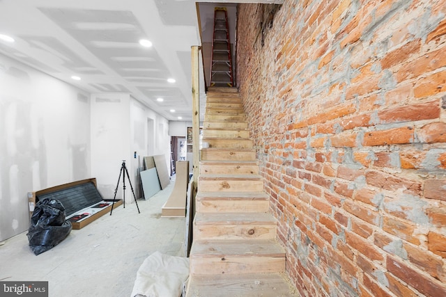 staircase featuring recessed lighting and brick wall