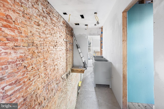 corridor featuring washer / clothes dryer and brick wall