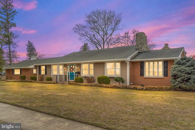 ranch-style home featuring a front lawn, brick siding, and a chimney