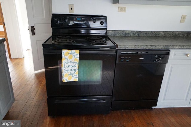 kitchen with dark wood finished floors, black appliances, white cabinets, and dark countertops